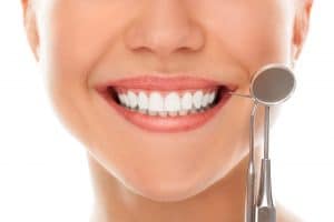 Person displaying bright white smile with dental mirror tool during dental examination or checkup.