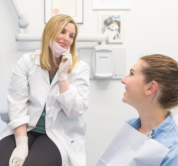 Female dentist in white coat consulting with patient in modern dental office.
