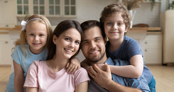 Happy family of four smiling together in a bright, modern dental office setting.
