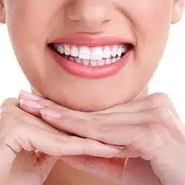 Close-up of person displaying bright white smile with hands near face, promoting dental health and cosmetic dentistry.